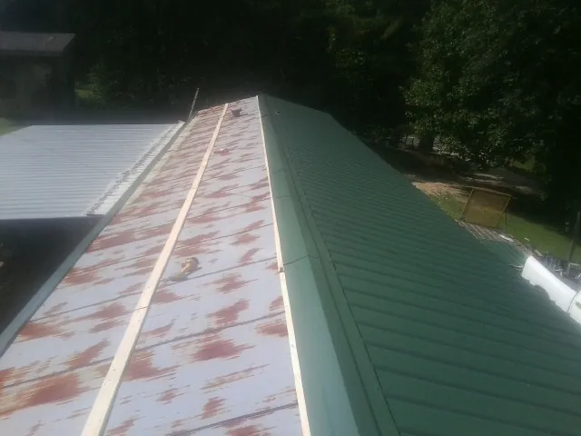 Old rusted panels beside newly installed green metal roofing — Wind Damage Roof Repair by Roofing Brothers in Odessa