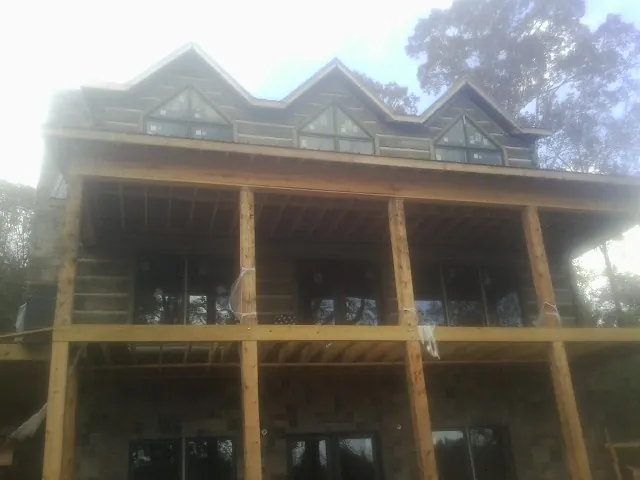 Dormers and porch framing on a large log home under construction — Roof Coating work by our crew in Odessa